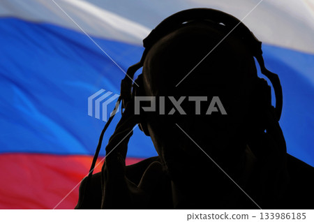 Silhouette of a man wearing headphones, eavesdropping secret agent, spy and scout, Russian flag, backlight 133986185
