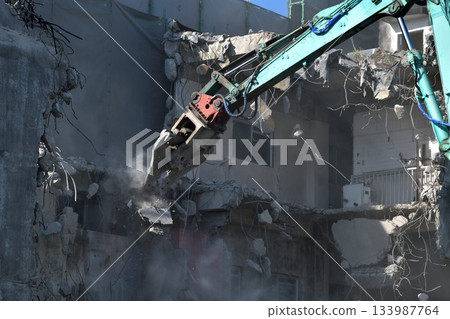 A dilapidated apartment building being demolished. Demolition work using large heavy machinery. A dilapidated apartment building being demolished. Demolition work using large heavy machinery. 133987764