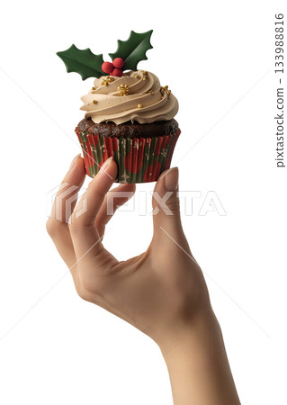 Single holiday cupcake with classic holly decoration held in hand, perfect for seasonal baking, cafe menus, or gift ideas 133988816