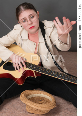 Female guitarist and street musician stretching out hand in hope of receiving donation for her musical performance. Her countenance directed towards camera, conveying sense of hope and anticipation Female guitarist and street musician stretching out hand in hope of receiving donation for her musical performance. Her countenance directed towards camera, conveying sense of hope and anticipation 133990130