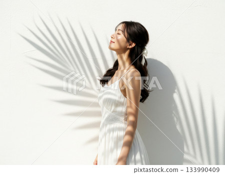 穿著白色連身裙的女子，以及一棵棕櫚樹的影子 133990409