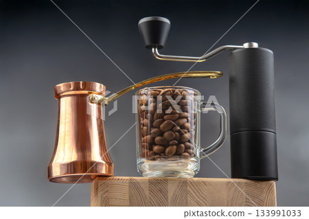 A stylish still life featuring a copper cezve, a glass mug filled with coffee beans A stylish still life featuring a copper cezve, a glass mug filled with coffee beans 133991033