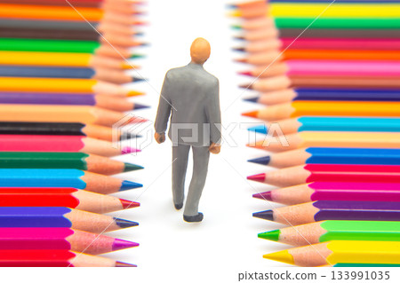 Rows of colorful pencils form a path where a small business figurine strides Rows of colorful pencils form a path where a small business figurine strides 133991035