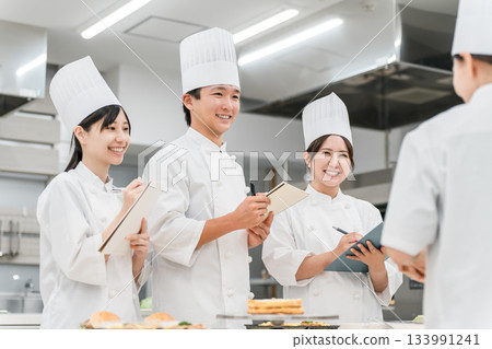 身著廚師制服的男女廚師在廚房裡研發菜單、產品和食譜。 133991241