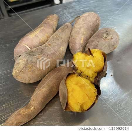 Roasted sweet potato with slightly charred skin and soft, golden interior, showcasing its warm color, tender texture, and natural sweetness in close-up detail 133992914