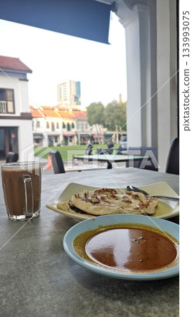 This is a group of food with Roti Canai, Teh Tarik and Curry 133993075