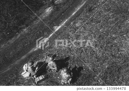 Men Dressed As US American Soldiers Of USA Infantry Of World War II sneaking around In spring Autumn Day. Soldiers prepare mortar for battle In dry grass. Aerial view elevated shot 133994478