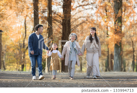 Autumn family photo: Smiling three-generation family in a forest of autumn leaves. Grandmother, grandchild and child couple walking hand in hand. Autumn family photo: Smiling three-generation family in a forest of autumn leaves. Grandmother, grandchild and child couple walking hand in hand. 133994713