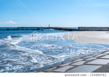 The sandy beach and waves of Kawarago Beach in Hitachi City, with the red lighthouse visible in the distance The sandy beach and waves of Kawarago Beach in Hitachi City, with the red lighthouse visible in the distance 133994761