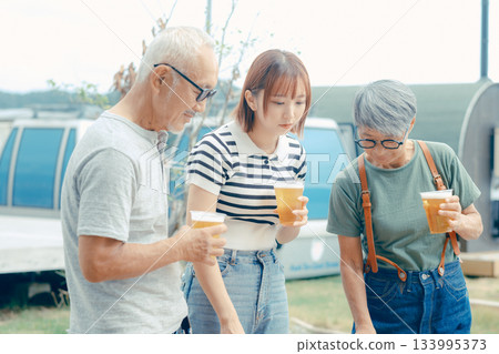 A scene of three people standing at the beach and toasting 133995373