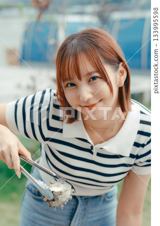 一位二十多歲的女子在海灘上烤海鮮 133995598