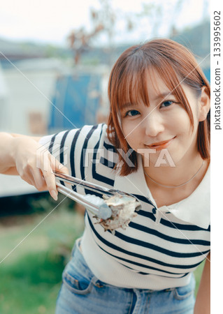 A woman in her 20s grilling seafood on the beach 133995602