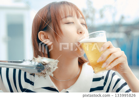 A woman in her 20s enjoying beer while grilling seafood A woman in her 20s enjoying beer while grilling seafood 133995826
