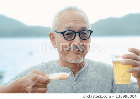 A scene of a senior man enjoying beer and shellfish dishes at the beach 133996004