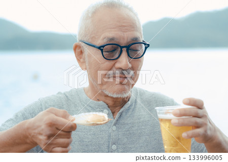 A scene of a senior man enjoying beer and shellfish dishes at the beach 133996005