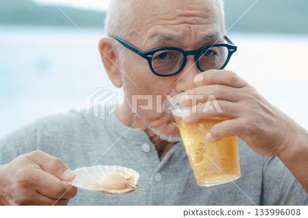 老人們在海灘上享用啤酒和貝類菜餚 133996008