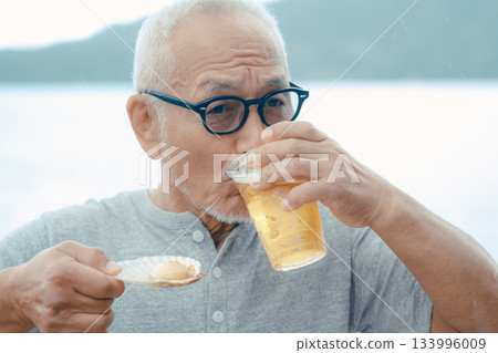 老人們在海灘上享用啤酒和貝類菜餚 133996009