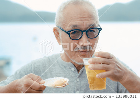 老人們在海灘上享用啤酒和貝類菜餚 133996011
