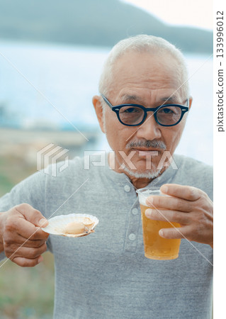老人們在海灘上享用啤酒和貝類菜餚 133996012