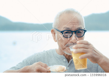 老人們在海灘上享用啤酒和貝類菜餚 133996016