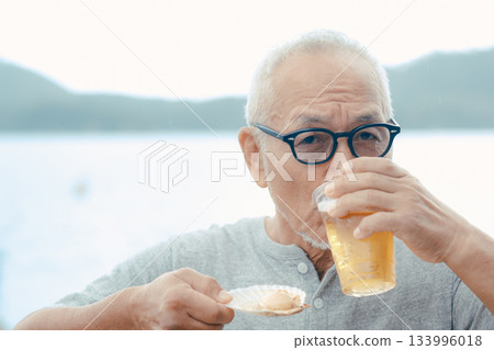 老人們在海灘上享用啤酒和貝類菜餚 133996018