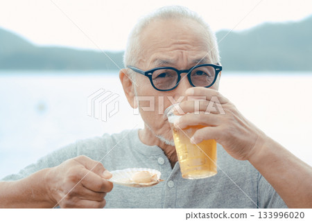 A scene of a senior man enjoying beer and shellfish dishes at the beach 133996020