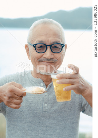 A scene of a senior man enjoying beer and shellfish dishes at the beach 133996025
