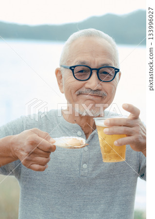 老人們在海灘上享用啤酒和貝類菜餚 133996027