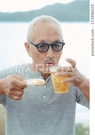 老人們在海灘上享用啤酒和貝類菜餚 133996029