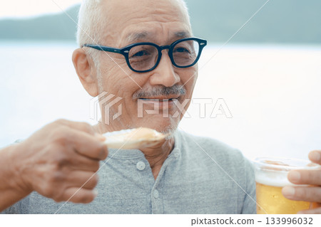 老人們在海灘上享用啤酒和貝類菜餚 133996032