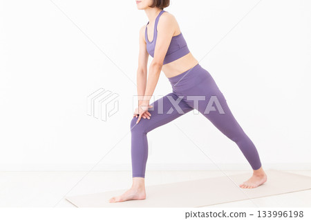 一位身穿瑜珈服的中年婦女正在做伸展運動 一位身穿瑜珈服的中年婦女正在做伸展運動 133996198
