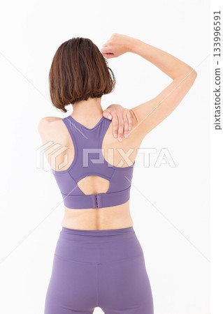 Middle-aged woman in yoga wear doing stretching exercises 133996591
