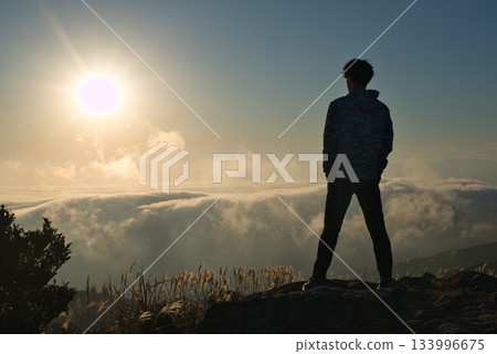 Backlit scene of a person gazing at a sea of clouds from the top of a mountain Backlit scene of a person gazing at a sea of clouds from the top of a mountain 133996675