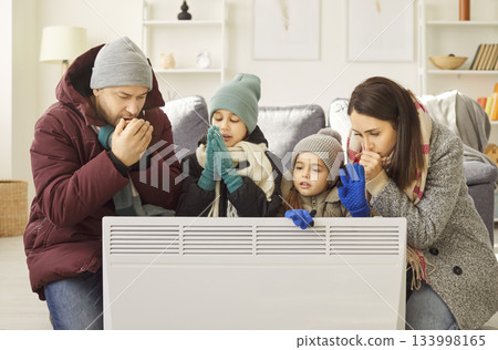 Disappointed family couple, children near heater at home freezing cool flat in warm upper wear 133998165