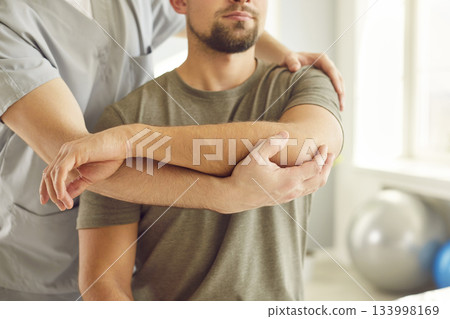 Chiropractor or physical therapist working with young man's arm in rehabilitation hospital. Chiropractor or physical therapist working with young man's arm in rehabilitation hospital. 133998169