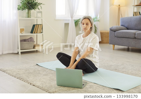Elderly Woman Training At Home With Online Coach Using Laptop For Fitness Elderly Woman Training At Home With Online Coach Using Laptop For Fitness 133998170
