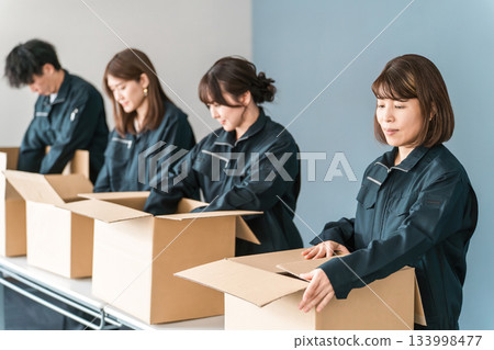 Male and female workers of transportation, logistics, courier, distribution, delivery, warehouse and delivery companies who pack items into cardboard boxes 133998477