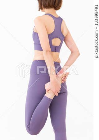 Middle-aged woman in yoga wear doing stretching exercises 133998491
