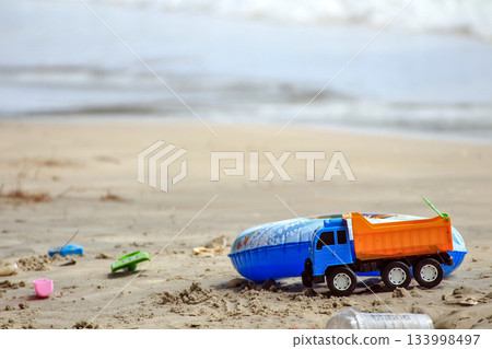 Toy truck with colorful rubber rings and sand toys on the beach by the sea 133998497