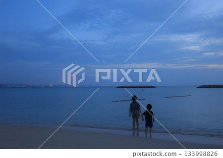 Children watching Naha fireworks from Chatan Sunset Beach, Okinawa Children watching Naha fireworks from Chatan Sunset Beach, Okinawa 133998826