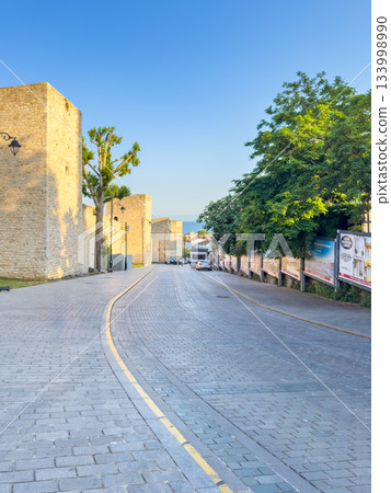 An old fortress stone wall and a cobbled street at dawn 133998990