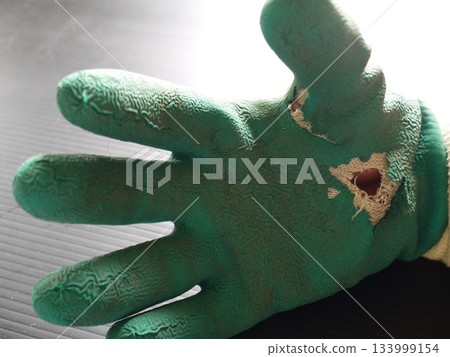 Worn-out work gloves with holes Worn-out work gloves with holes 133999154