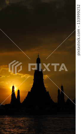 Vertical Silhouette of Wat Arun (Temple of Dawn) Prang Against a Golden Sunset Sky Vertical Silhouette of Wat Arun (Temple of Dawn) Prang Against a Golden Sunset Sky 133999252