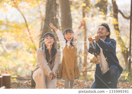 Smiling family enjoying playing with fallen leaves in autumn park, portrait of happy autumn memories of parents and children 133999391