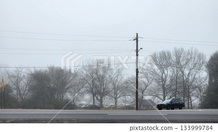 Foggy Street Scene With Power Lines, Trees, And Cars On A Quiet Road In Winter Dusk 133999784
