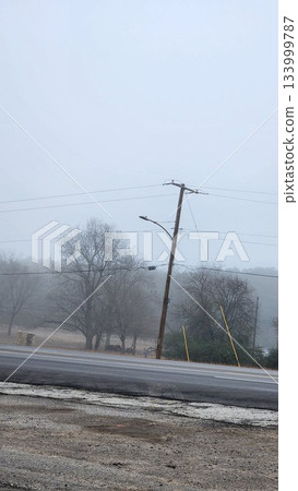 Foggy Street Scene With Power Lines, Trees, And Cars On A Quiet Road In Winter Dusk Foggy Street Scene With Power Lines, Trees, And Cars On A Quiet Road In Winter Dusk 133999787