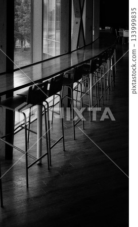 High stools lined up at a counter by the window and the window (monochrome) High stools lined up at a counter by the window and the window (monochrome) 133999835