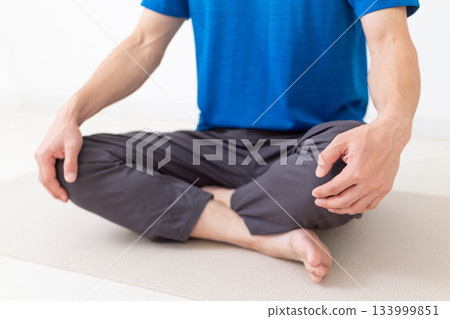 一位身穿T恤的中年男子盤腿而坐 一位身穿T恤的中年男子盤腿而坐 133999851