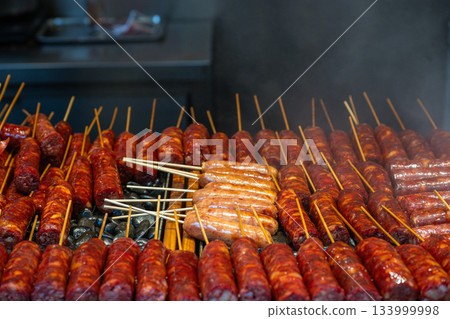 Street vendors grill spicy skewers in a market 133999998
