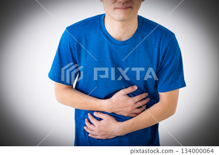 A middle-aged man wearing a T-shirt suffering from stomach pain 134000064